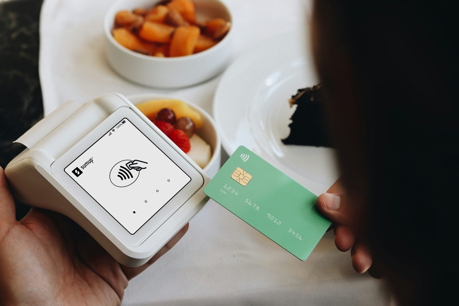 A person holding a credit card next to a bowl of food